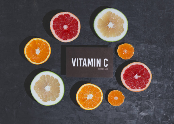 A set of natural products rich in vitamin C ascorbic acid. Healthy food concept. Cardboard sign with the inscription. Black background. - Photo, Image