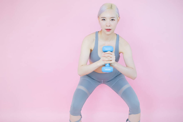 mooie aziatische vrouw op roze achtergrond, fitness sport en recreatie concept - Foto, afbeelding