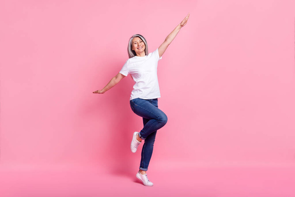 Photo of shiny funky age woman dressed white outfit smiling dancing jumping isolated pink color background - Foto, Imagem