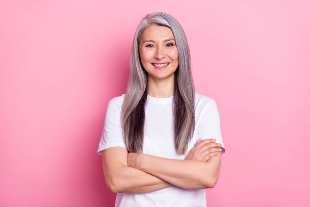 Photo portrait of senior business woman smiling with crossed hands isolated on pastel pink color background - Фото, зображення