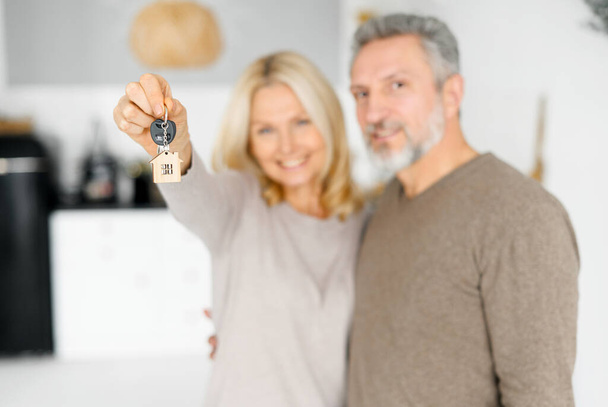 Happy cheerful middle-aged couple holds keys from new property - Photo, image