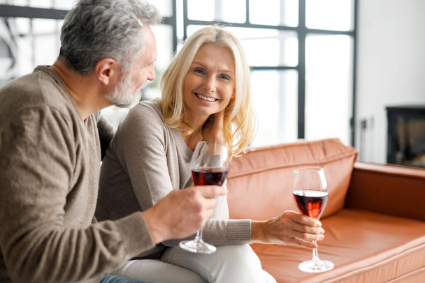 Harmonious mature married couple with wine having romantic date - Фото, зображення