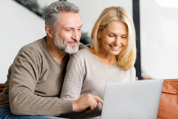 Middle-aged couple sits on the sofa and watching at the screen - Photo, image