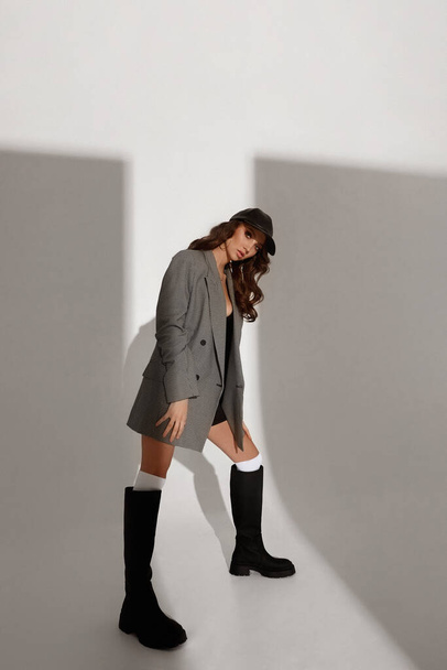 A young gorgeous woman in stylish boots and trendy blazer over white background - Φωτογραφία, εικόνα