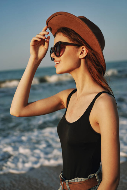 cheerful woman in sunglasses and a hat by the ocean walk summer - Zdjęcie, obraz