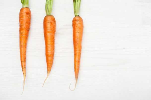 Raw carrots on white wooden table  - Zdjęcie, obraz