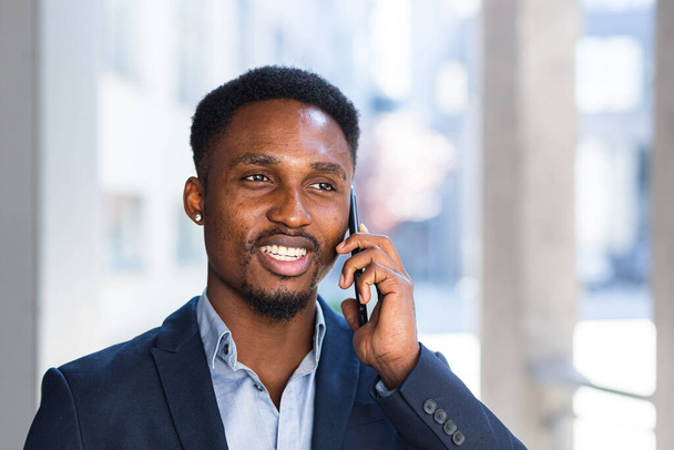 close up portrait of african businessman talking on the phone and smiling from success in business suit - Foto, immagini