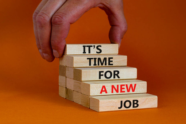 It is time for a new job symbol. Wooden blocks with words It is time for a new job. Beautiful orange background, copy space. Businessman hand. Business, time for a new job concept. - Foto, afbeelding