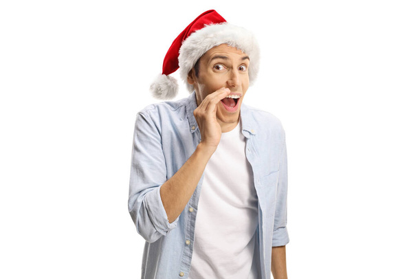 Young man with a santa claus hat whispering a secret isolated on white background - Foto, imagen