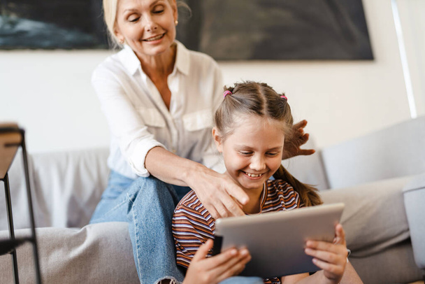 White mother and daughter using tablet computer together at home - Valokuva, kuva