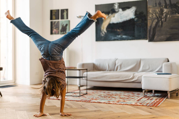 White preteen girl standing on her arms while making fun at home - Photo, Image