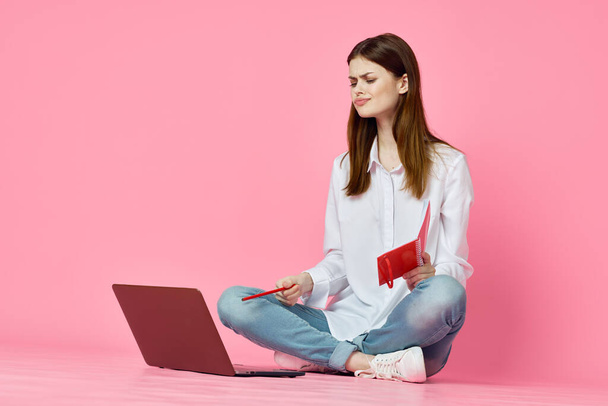 woman sitting on floor with laptop shopping entertainment pink background - Фото, зображення