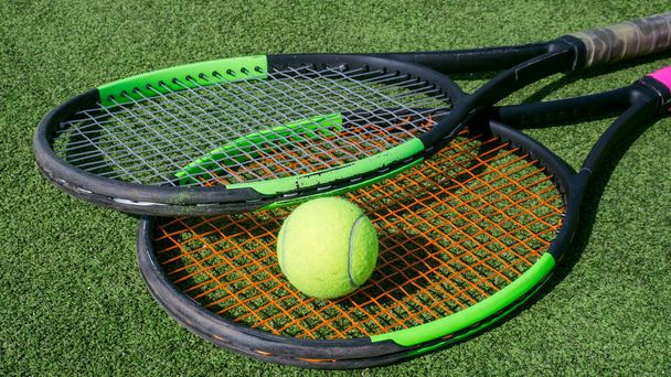 tennis ball and racket lie on the green court close up. - Foto, imagen