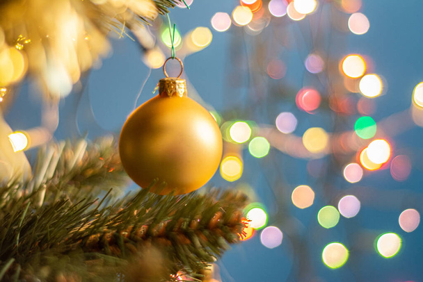 Closeup of a decorative ornament hanging from the Christmas tree covered with lights. - 写真・画像
