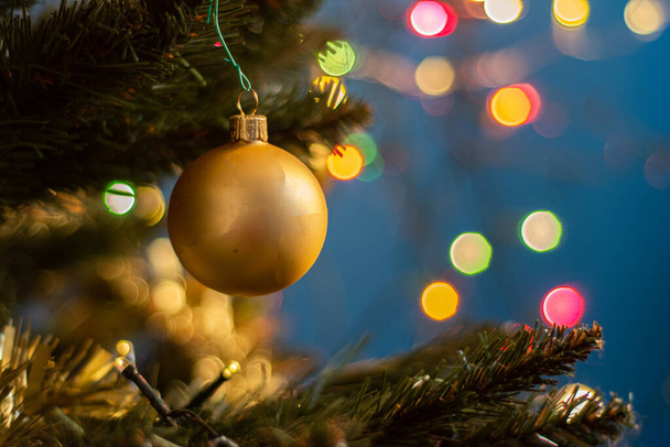 Nahaufnahme einer dekorativen Zierde, die am Weihnachtsbaum hängt und mit Lichtern bedeckt ist. - Foto, Bild