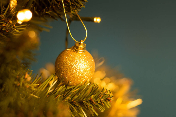 Closeup of a decorative ornament hanging from the Christmas tree covered with lights. - Foto, afbeelding