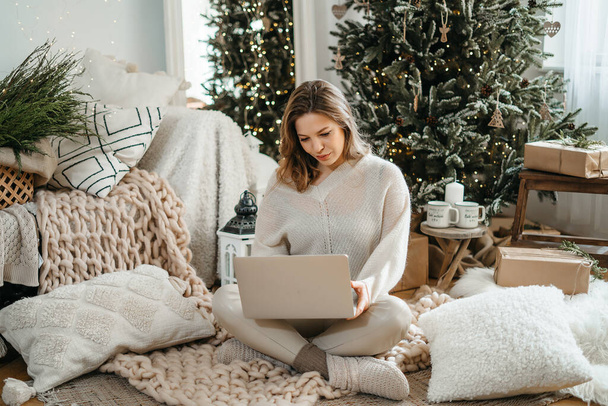 Head shot smiling young caucasian woman in warm winter clothes looking at computer tablet scree, reading Christmas wishes or congratulating friends with New Year night online in social network. - Photo, image