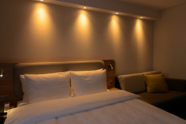 Luksusowy nowoczesny pokój hotelowy, bez osób, przytulne ciepłe poduszki kolorów, wykładziny, zasłony, tapicerka ścienna i meble. Koncepcja relaksu podczas podróży. - Zdjęcie, obraz