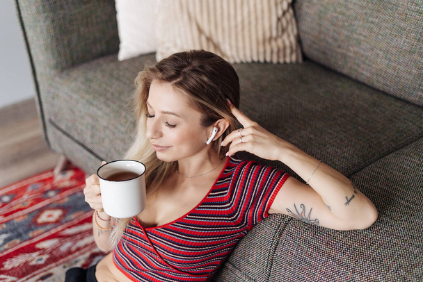 Young Woman listening music sitting near sofa at home - Photo, image