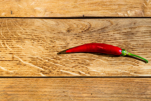 Red hot peppers on wooden table - Foto, afbeelding