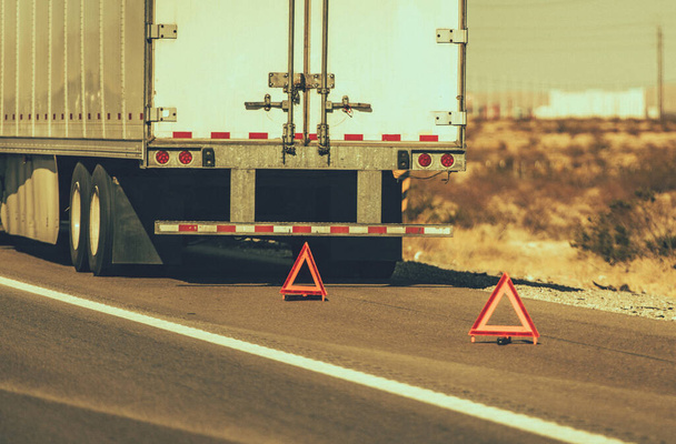 Súlyos szállítási téma. Törött kamion az autópálya pótkocsi oldalán Bezárás és figyelmeztető háromszögek. Útmenti segítségnyújtás. - Fotó, kép