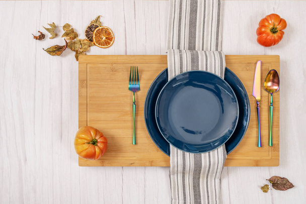 Bild von oben von Speisesaal-Service mit blauen Tellern, weißem und grauem Tuch, schillernden rosa Tomaten und Herbstblättern - Foto, Bild