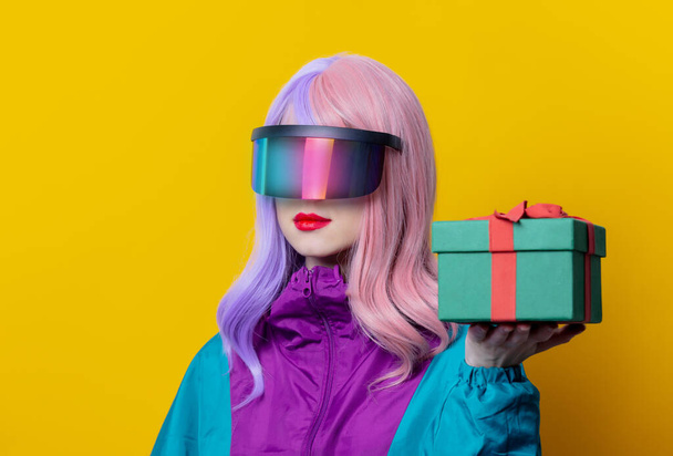 Stile donna in VR occhiali e 90s tuta sportiva tenere scatola regalo su sfondo giallo - Foto, immagini
