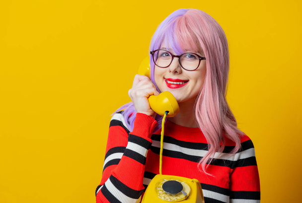Lila hajú lány piros pulóver tartsa tárcsázza telefon sárga háttér - Fotó, kép