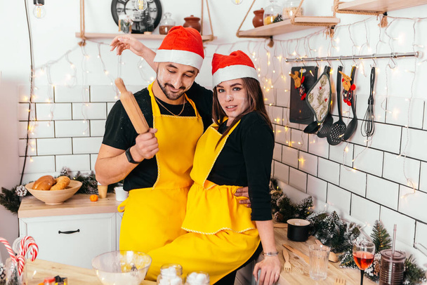 Krásný romantický pár stojící kuchyně líbání špinavá mouka vaření večeře domácí atmosféra Nový rok klobouk vánoční dekorace nálada dovolená strana slaví koncept zimní večer kopírovat prostor - Fotografie, Obrázek