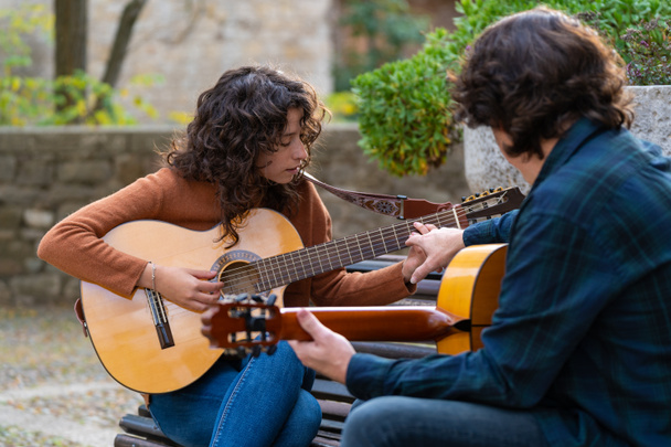 Дівчинка, яка вчиться грати на іспанській гітарі на вулиці з вчителем. - Фото, зображення