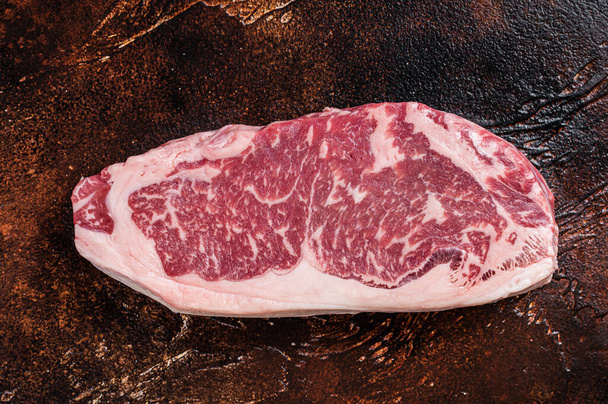 Syrový steak z New Yorku nebo striptýz na řeznickém stole. Tmavé pozadí. Horní pohled - Fotografie, Obrázek