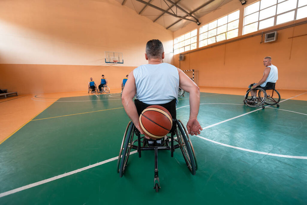 Disabled War or work veterans mixed race and age basketball teams in wheelchairs playing a training match in a sports gym hall. Handicapped people rehabilitation and inclusion concept.Hi quality photo - Zdjęcie, obraz