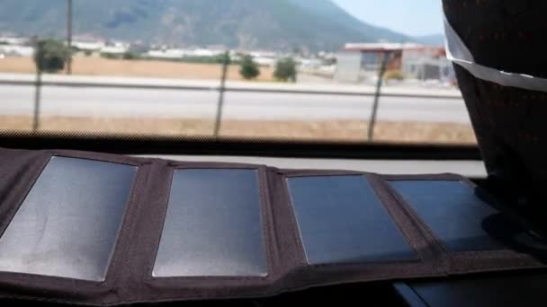 Πτυσσόμενο τουριστικό ηλιακό πάνελ από διάφορα τμήματα στο παράθυρο με φόντο την πόλη. Η μπαταρία φωτίζεται από τον ήλιο. Εναλλακτική ενέργεια. - Πλάνα, βίντεο