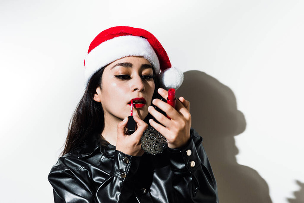 young latin woman putting on makeup for christmas party on white background in Mexico Latin America - Foto, afbeelding