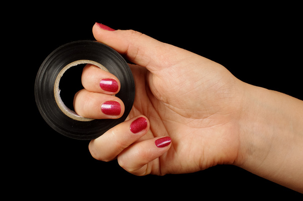 Female hand holding roll of duct tape isolated on the black - Photo, Image