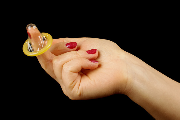 Kädestä pitäminen kääritty kondomi mustalla pohjalla
 - Valokuva, kuva