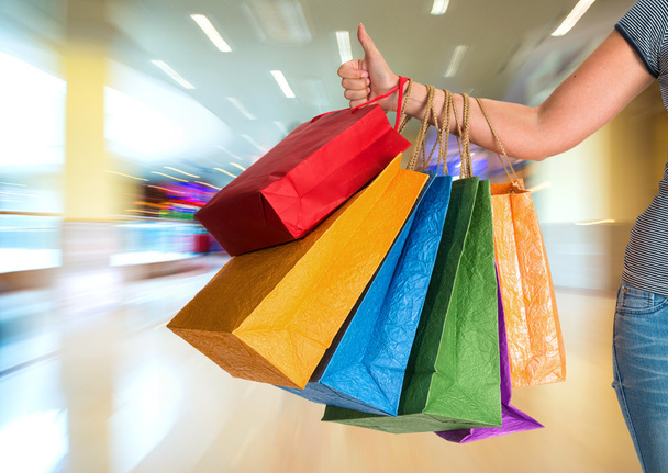 Mujer mostrando el pulgar hacia arriba y sosteniendo bolsas de compras
 - Foto, imagen