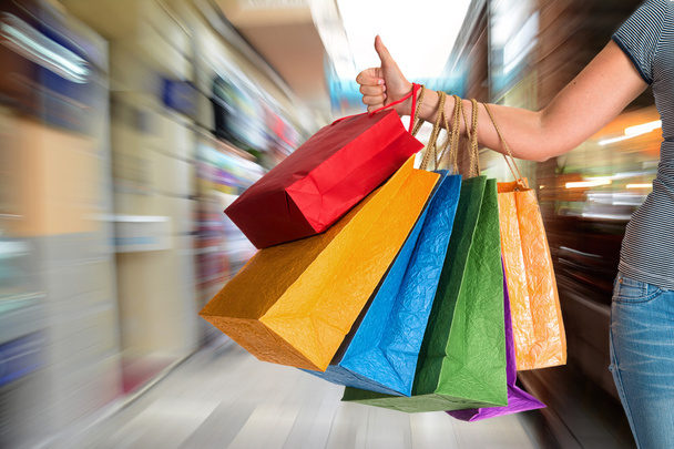 Woman showing thumb up and holding shopping bags - Foto, afbeelding