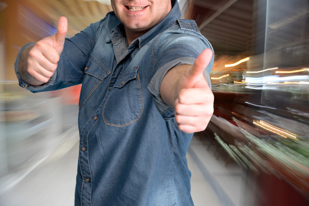 Молодий чоловік жестикулює великі пальці в торговому центрі
 - Фото, зображення