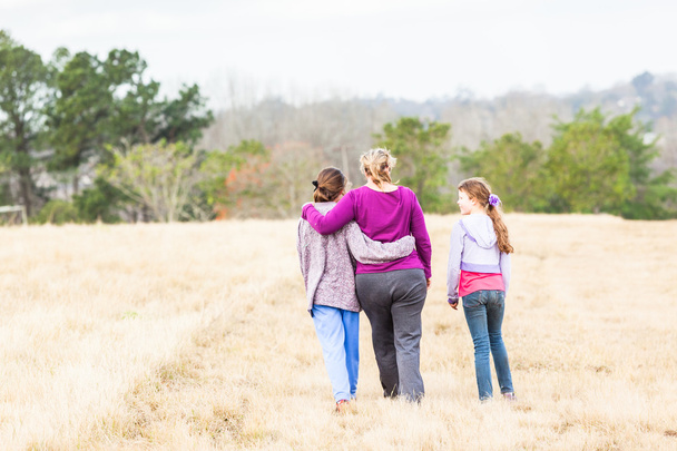Madre Hijas caminando abrazándose al aire libre
 - Foto, Imagen