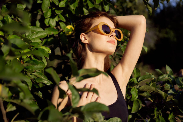 alegre mujer usando gafas de sol verde hojas naturaleza verano posando - Foto, imagen