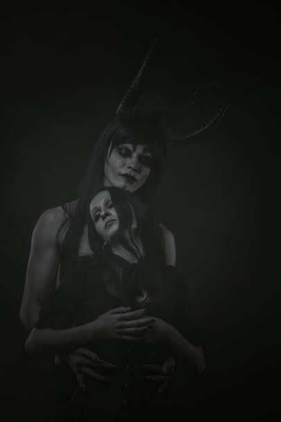Рогатый демон обнимает милую готическую девушку на тёмном фоне - Фото, изображение