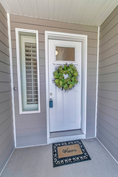 Esterno di un ingresso di una casa con porta d'ingresso bianca e rivestimenti in legno grigio - Foto, immagini