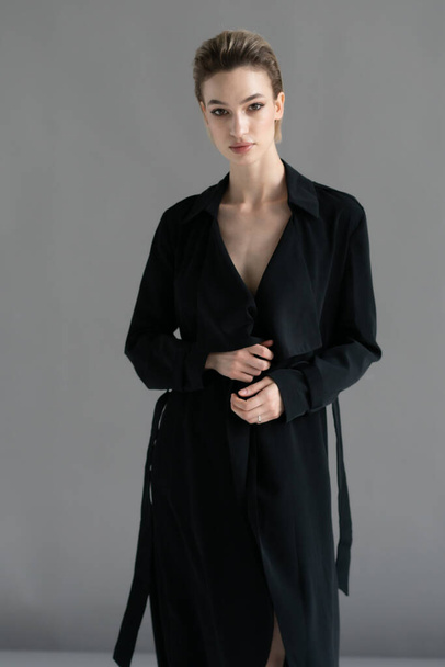 giovane bella donna posa in un mantello nero in studio - Foto, immagini