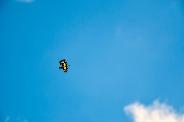 Libélula colorida volando espontánea y felizmente al aire libre contra un cielo azul y nubes flotantes. - Foto, imagen