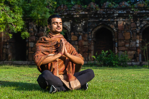 un jeune homme musclé faisant du yoga et une méditation profonde sur l'herbe par une journée ensoleillée - Photo, image