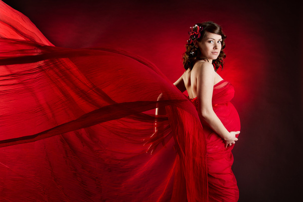 Pregnant woman in red waving dress - 写真・画像