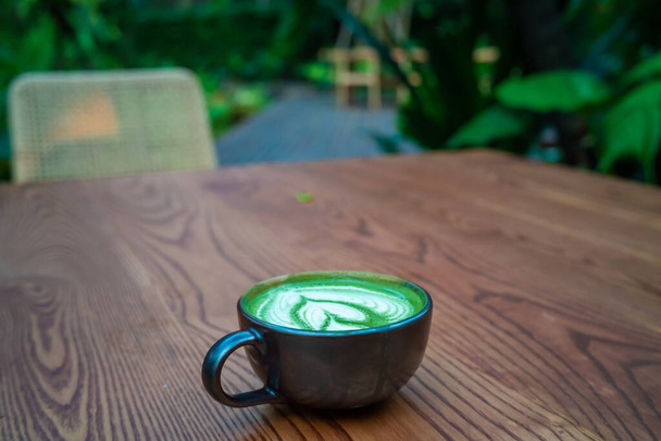Gorąca matcha zielona herbata l; atte sztuki na drewnianym stole gorący napój kafeinowy - Zdjęcie, obraz