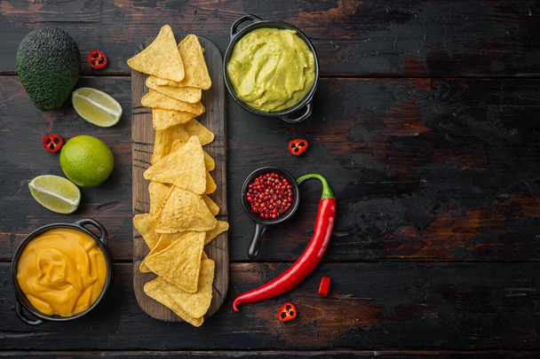 Nacho tortilla with cream sauce served with guacamole and cheese dip sauce, on old wooden table, top view or flat lay with copy space for text - Fotografie, Obrázek