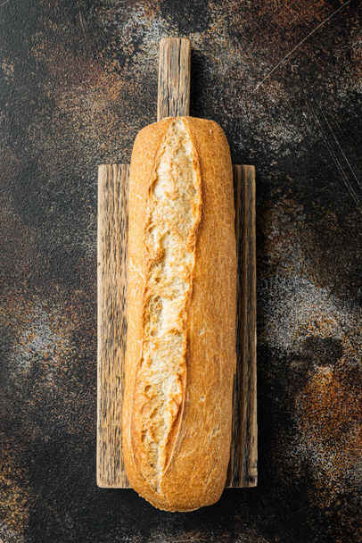Целый хлеб багет зерна, на старом темном деревенском фоне, вид сверху лежал плоский - Фото, изображение